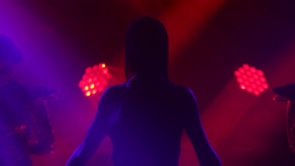 Silhouette of Dancing Joan of Arc on Stage in a Dark Studio with Smoke and Neon Lighting. A Bright