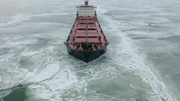 Aerial Above Epic Huge Steel Icebreaker Breaks Ice By Bow of Ship and Floats in Large Sea Ice Floes