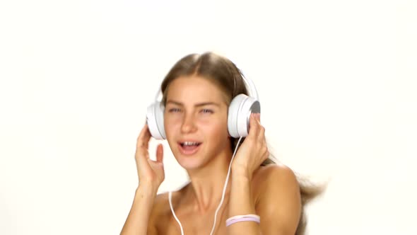 Beautiful Female in Headphones Listening To the Music with Fluttering on the Wind Hair Over White