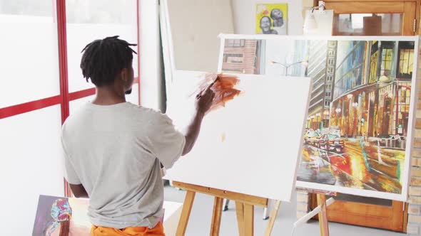 African american male painter painting on canvas in artist studio