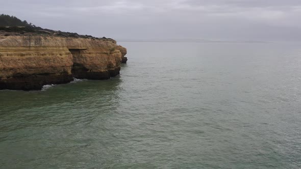 Cliffs in Fontainhas beach of South Portugal seen from the side, Aerial dolly in reveal shot