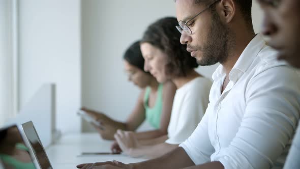 Side View of African American Man in Eyeglasses Typing on Laptop