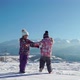 Charming Kids in Outwear Running on Snowy Terrain with Beautiful Mountains on Background in Sunshine - VideoHive Item for Sale