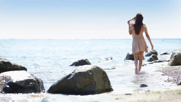 A beautiful young woman on the beach turns to the camera and flashes a winning smile