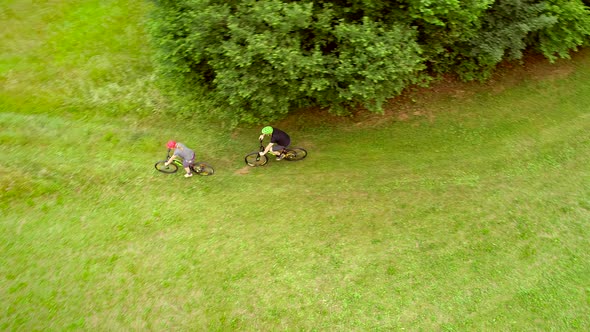 Aerial view of man and woman cycling on dirt road in the summertime.
