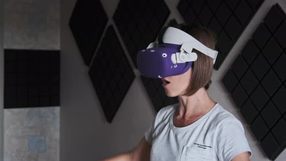 Young Woman in a VR Helmet Plays a Game at Home