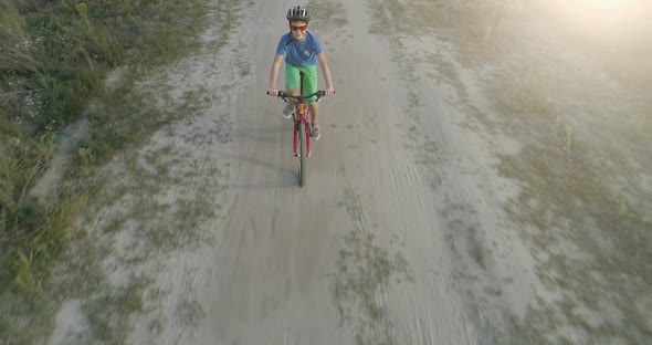 Boy Ride a Bicycle on Country Road at Sunset. Aerial View. , FHD