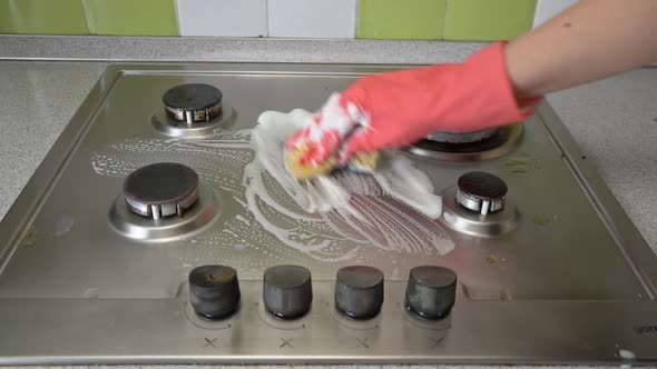 Housewife in Gloves Washes the Gas Stove in Kitchen with a Washcloth and Foam