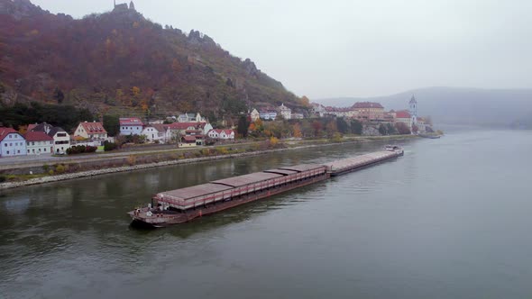 Cargo Pusher Boat on a River Transporting Cargo and Goods Past a Town