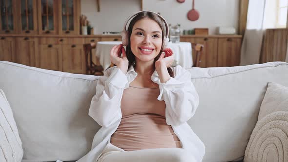 Cheerful Pregnant Woman Listens to Music in Headphones