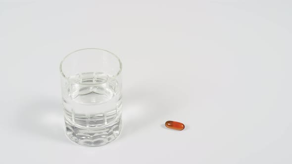 Pill next to a glass of water