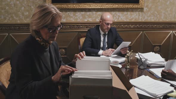 Senior Female Lawyer Looking Over File Folders in Archival Box