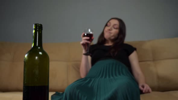 Wine Bottle Against Blurry Drunk Woman Sipping Alcohol