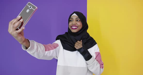 Portrait of Smiling African Black Muslim Girl Posing at Color Studio Background Taking Selfie Photo