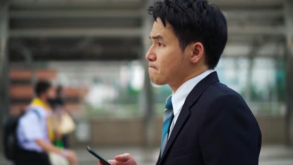 serious man walking and using a smartphone in the city