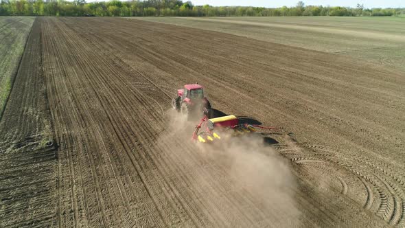 Aerial View of Tractor Working in the Field with a Modern Sowing Seeds Machine in a Newly Plowed