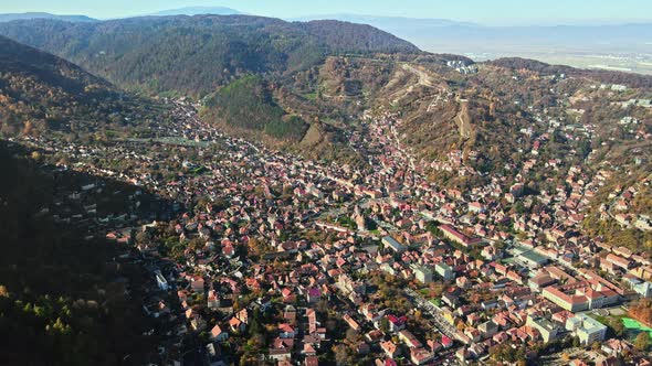 Aerial drone view of Brasov, Romania. Residential buildings, yellowed trees, Carpathians