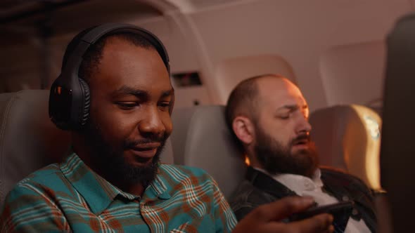 African American Tourist Using Smartphone to Have Fun on Flight