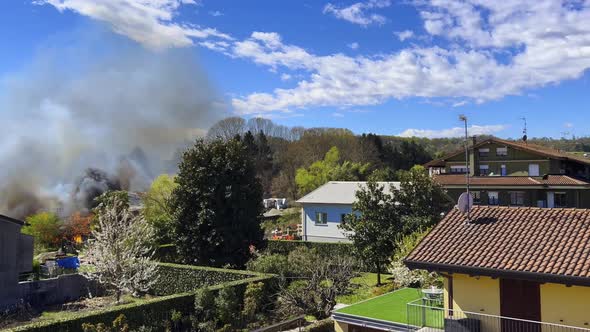 House on fire with flames and black smoke rising in the sky. Zoom out