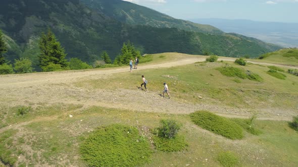 Drone View of Group of Hikers Reaching the Top of a Hill with Forested Mountains Around