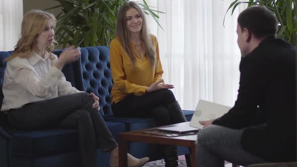 Confident Senior Woman Talking As Her Younger Cheerful Colleague Smiling and Supporting Conversation