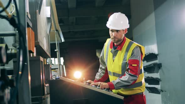 Metallurgy Specialist in Safety Wear Is Operating a Console