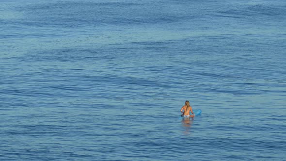 A young woman surfing in a bikini on a longboard surfboard.