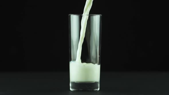 Milk Pouring Into Glass Close Up Isolated on Black Background Slow Motion