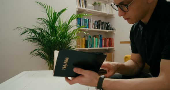 Christian Religious Man Prays and Reads Holy Bible at Home Studying Scripture / Videohive