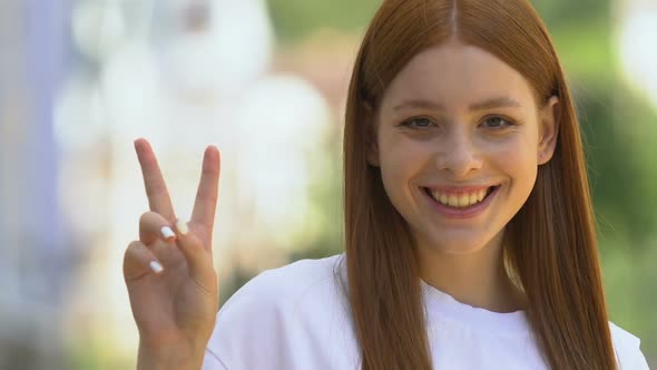 Pretty Smiling Female Teen Showing Peace Gesture, Millennial Generation Freedom