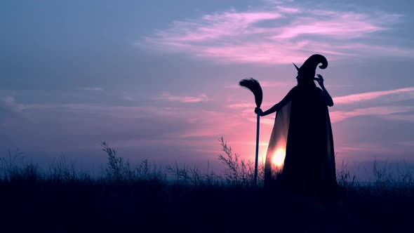 Woman in a Witch Costume and Broom Posing at Night on the Hill