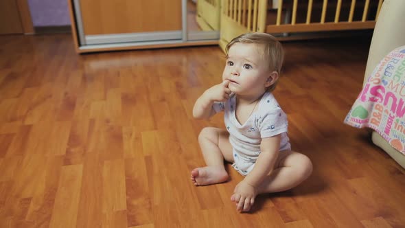 Baby boy sitting on the floor in the room.