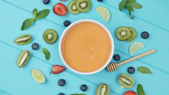 Orange Smoothie Garnished with Mint and Strawberries with Kiwi