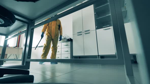 Worker Disinfects Room, Using a Sprayer.