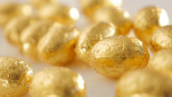 Traditional Easter eggs made of chocolate wrapped in golden foil 4K 2160p 30fps UltraHD panning foot