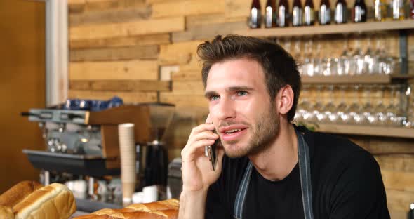 Male waiter talking on mobile phone at counter 4k