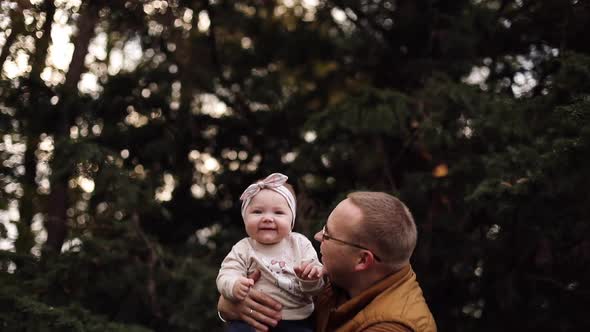 Loving Mother Kissing Her Daughter on Father's Hands in Park.