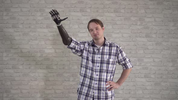 Positive Young Man Waves a Cyber Prosthetic Hand