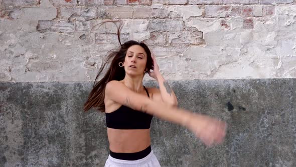 Female hip-hop dancer performing in front of flaking wall