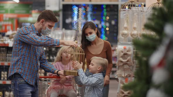 A Happy Family in Medical Masks in the Store Buys Christmas Decorations and Gifts in Slow Motion