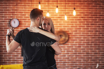 Bachata, merengue, salsa. Two elegance pose on cafe with brick walls