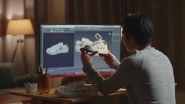 Male Footwear Designer Holding And Looking At The Colourful Pattern Sneakers While Designing