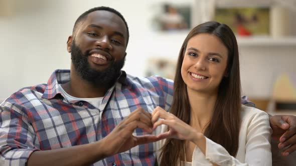 Cheerful Mixed-Race Couple Showing Heart Sign Made With Hands at Camera, Love