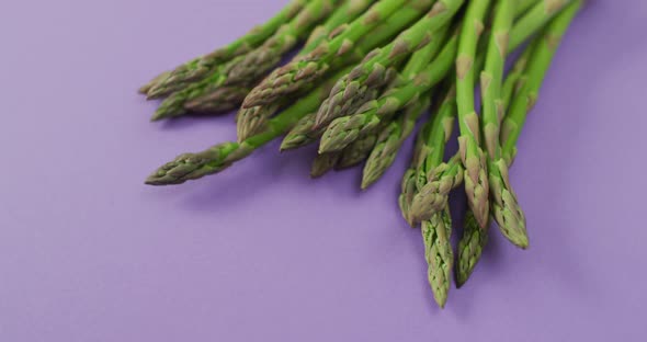 Video of close up of fresh asparagus with copy space over lilac background