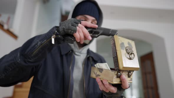 Closeup of Robber Opening Decorative Box with Money Using Weapon