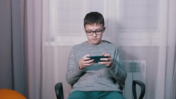 Surprised Child in Glasses Watching a Video in a Mobile App on a Smartphone