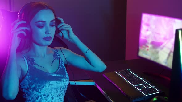 Sexy Young Woman Putting on Her Headphones and Playing Games in Gaming Club