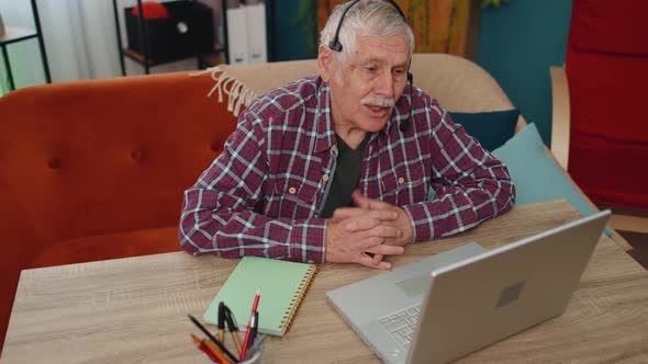 Senior Man Freelance Wear Headphone Make Video Call Talking Teaching at Laptop at Home Office