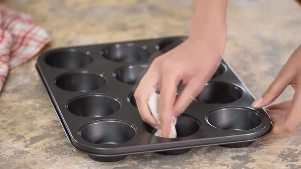 Woman Spreading Oil on Muffins Moulds To Make Delicious Cupcakes, Muffins. Homemade Pastries.