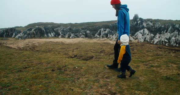 Young Adult Woman Walk with Daughter on Ocean Edge Aside the Cliff